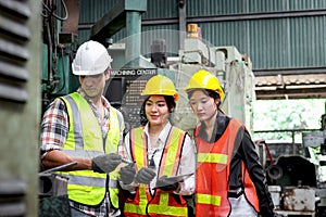 Group of male and female industrial engineer workers with helmet and safety vest inspecting engine at manufacturing plant industry