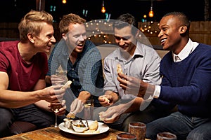 Group Of Male Friends Enjoying Night Out At Rooftop Bar