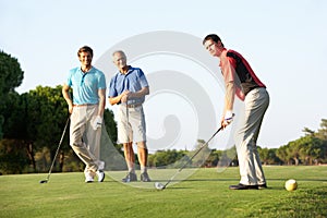 Group Of Male Golfers Teeing Off