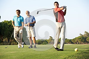 Group Of Male Golfers Teeing Off
