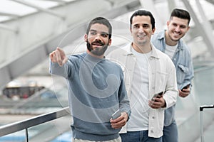 Group Of Males Using Cellphones Pointing Finger Aside In Airport