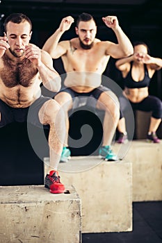 Group of man and woman jumping on fit box at gym