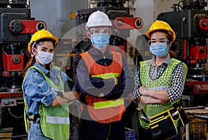 Group of man and woman workers with mask stand with confident action in the factory workplace and various machine as background