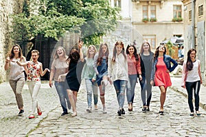 Group of many happy women walking having fun on background of old european city street, celebrating friendship concept, moments of