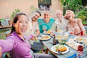 Group of mature adult friends smiling taking a selfie on a barbeque party celebration at home backyard. Middle age