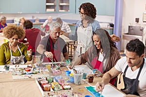 Group Of Mature Adults Attending Art Class In Community Centre With Teacher