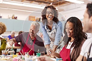 Group Of Mature Adults Attending Art Class In Community Centre With Teacher