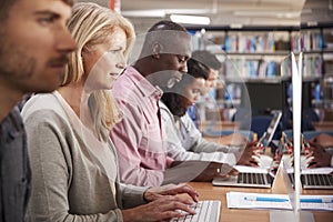 Group Of Mature College Students Working On Computers In Library