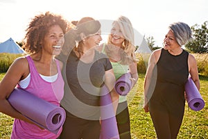 Group Of Mature Female Friends On Outdoor Yoga Retreat Walking Along Path Through Campsite photo