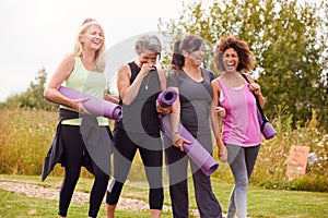 Group Of Mature Female Friends On Outdoor Yoga Retreat Walking Along Path Through Campsite