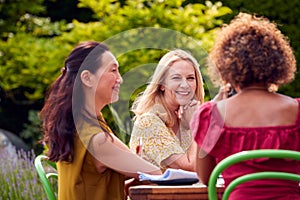 Group Of Mature Female Friends Talking Around Table At Summer Dinner Party In Garden At Home