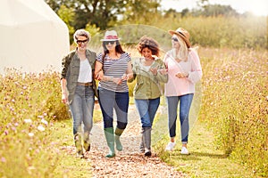 Group Of Mature Female Friends Walking Along Path Through Yurt Campsite photo