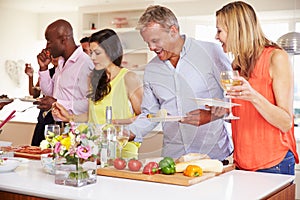 Group Of Mature Friends Enjoying Buffet At Dinner Party