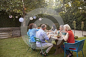 Group Of Mature Friends Enjoying Outdoor Meal In Backyard