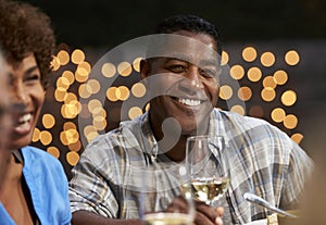 Group Of Mature Friends Enjoying Outdoor Meal In Backyard