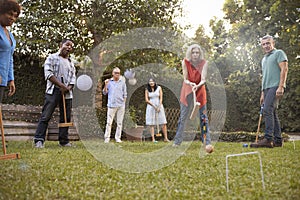 Group Of Mature Friends Playing Croquet In Backyard Together