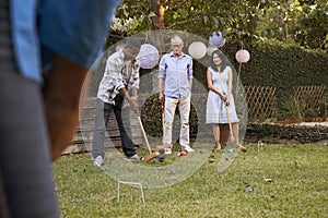 Group Of Mature Friends Playing Croquet In Backyard Together