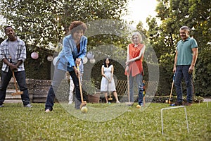 Group Of Mature Friends Playing Croquet In Backyard Together