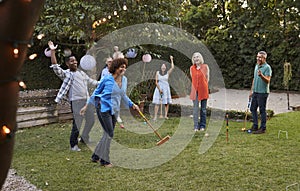 Group Of Mature Friends Playing Croquet In Backyard Together