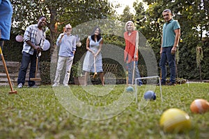 Group Of Mature Friends Playing Croquet In Backyard Together