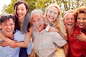 Group Of Mature Friends At Surprise Birthday Party For Woman In Garden With Cake And Champagne