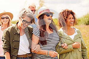 Group Of Mature Friends Walking Along Path Through Yurt Campsite