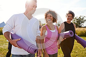 Group Of Mature Men And Women With Exercise Mats At End Of Outdoor Yoga Class photo