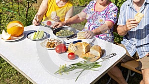 A group of mature people dine with natural products at a table in the garden