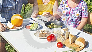 A group of mature people dine with natural products at a table in the garden