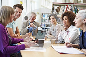 Group Of Mature Students Collaborating On Project In Library photo