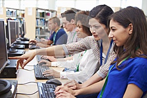 Group Of Mature Students Working At Computers With Tutor
