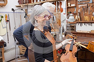 Group of mature violin maker in pose