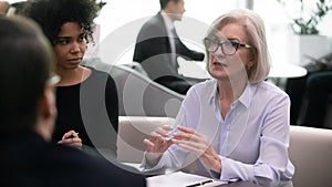 During group meeting multiethnic businesspeople listen middle-aged female leader