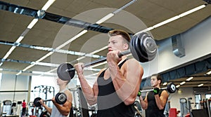 Group of men flexing muscles with barbell in gym