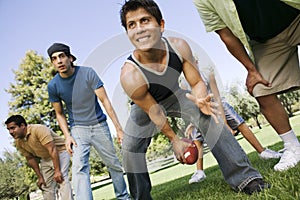 Group of men playing football in park low angle view.