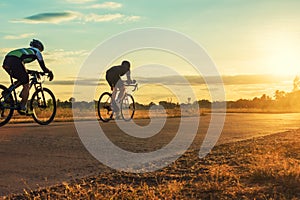 Group of men ride bicycles at sunset with sunbeam