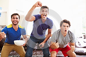 Group Of Men Sitting On Sofa Watching Sport Together