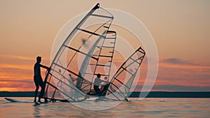 Group of men are using sailboard to float in the lake