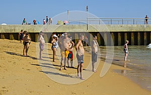 A group of men and women with large bellies gaze out to sea from the beach at the Old Town in Albuferia in Portugal