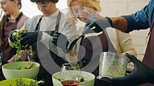 Group of men and women making dishes in cookery class working together enjoying hobby