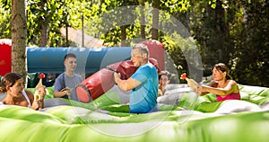 Group of men and women playing funny game in summer amusement park