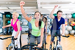 Group of men and women spinning on fitness bikes in gym