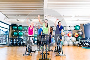 Group of men and women spinning on fitness bikes in gym