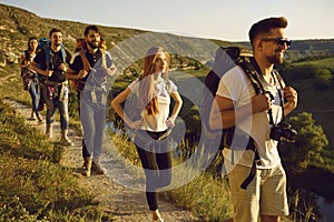 Group of men and women walk in a row along the trail during a walking tour of the mountains.