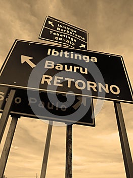 Group of metal signs indicating multiple locations in a confuse way at brazilian countryside [Sepia]