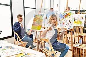 Group of middle age artist at art studio pointing fingers to camera with happy and funny face