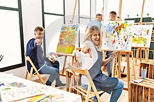 Group of middle age artist at art studio pointing to you and the camera with fingers, smiling positive and cheerful