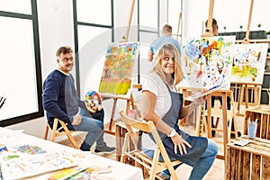 Group of middle age artist at art studio smiling looking to the side and staring away thinking