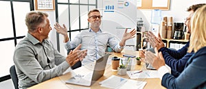 Group of middle age business workers smiling and clapping to partner at the office