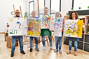 Group of middle age draw students smiling happy holding drawing canvas at art studio